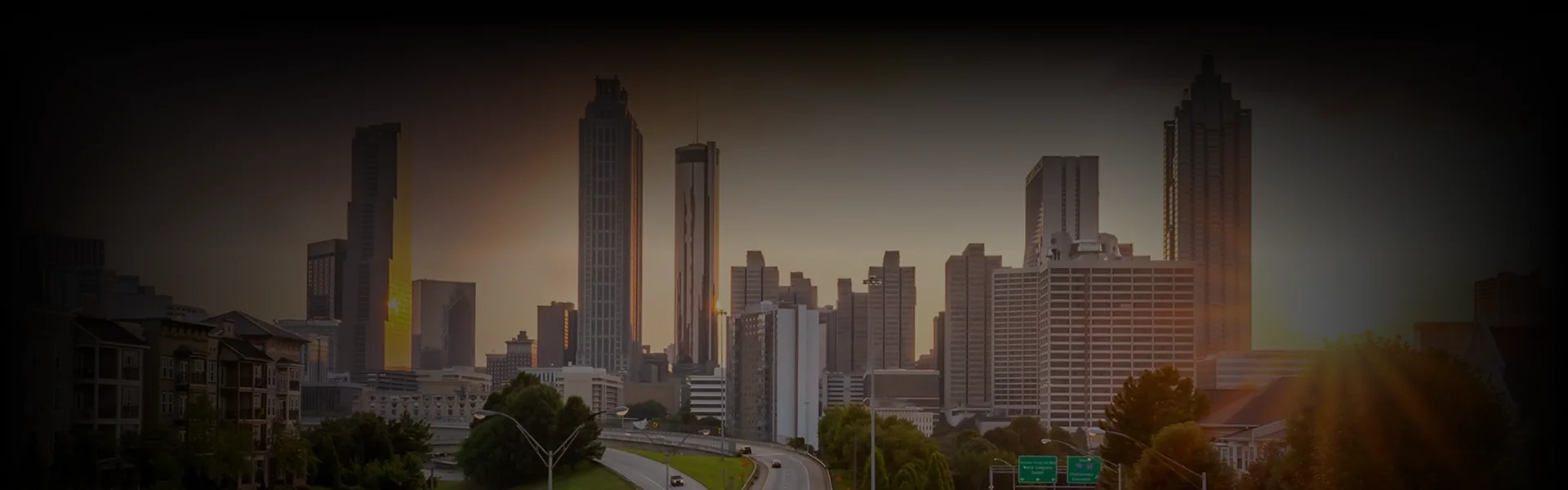 Downtown Georgia skyline at golden hour, with tall lit buildings viewed from a wide cityscape angle, showcasing premium Georgia Car Service.